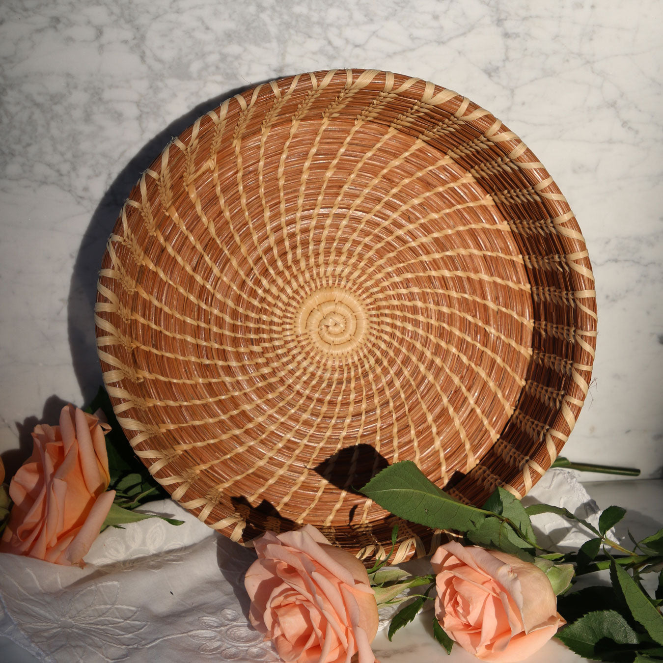 Woven basket with peach roses on a marble surface