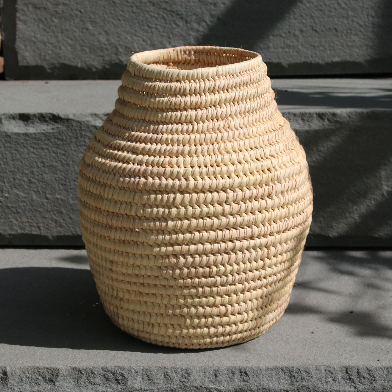 Woven beige vase on a stone surface